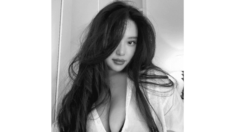 Stripchat linbaelin wearing an erotic blouse that highlights her massive cleavage and impressive big tits in a student-themed setting.